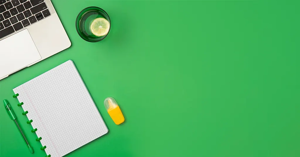 نمای بالای میز کار خلوت با رنگ سبز و دفتر و خودکار سبز